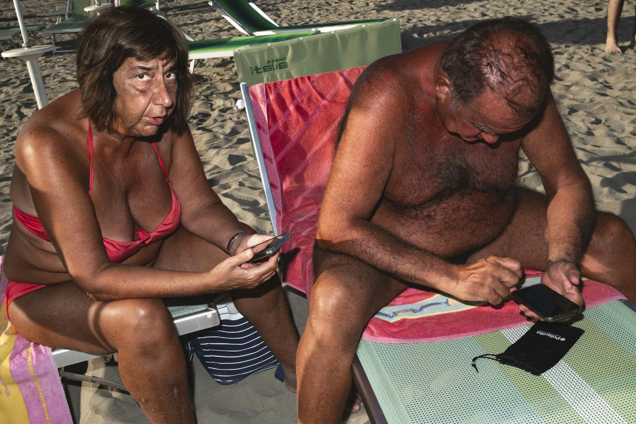 woman and man on sun loungers using phones