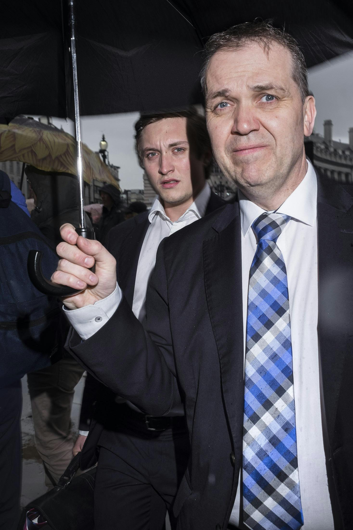 Two business men under an umbrella in suits in Piccadilly Circus, London.