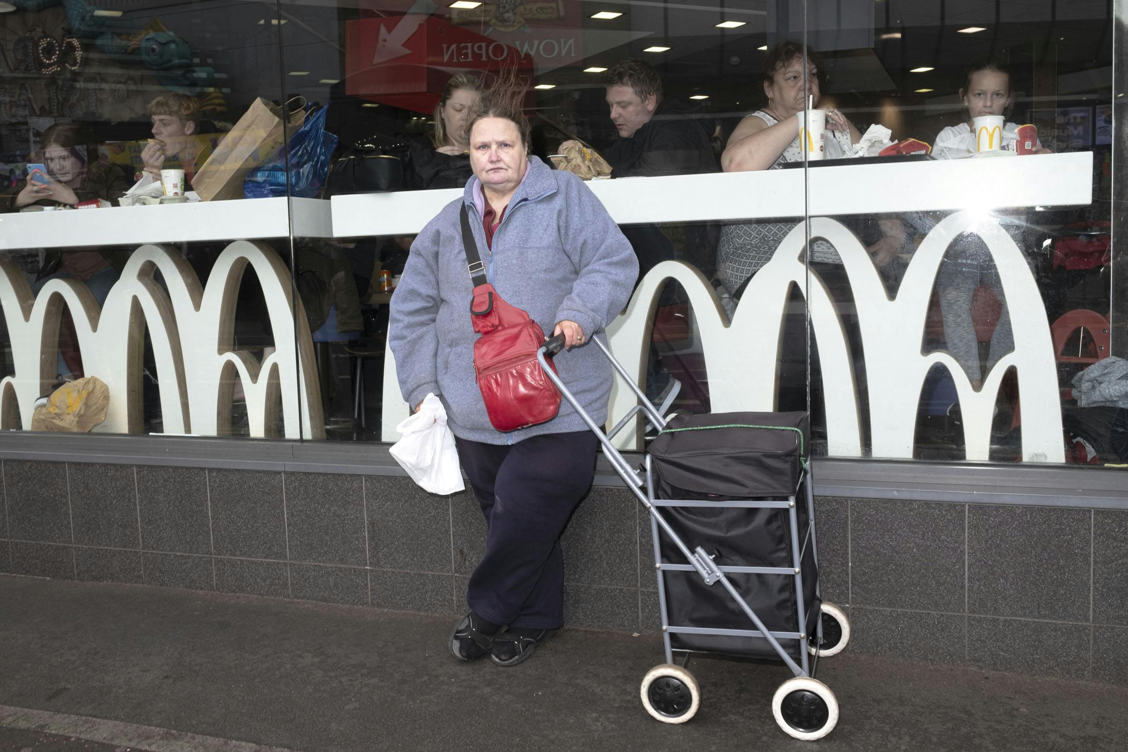 British woman with trolly outside Mcdonalds 