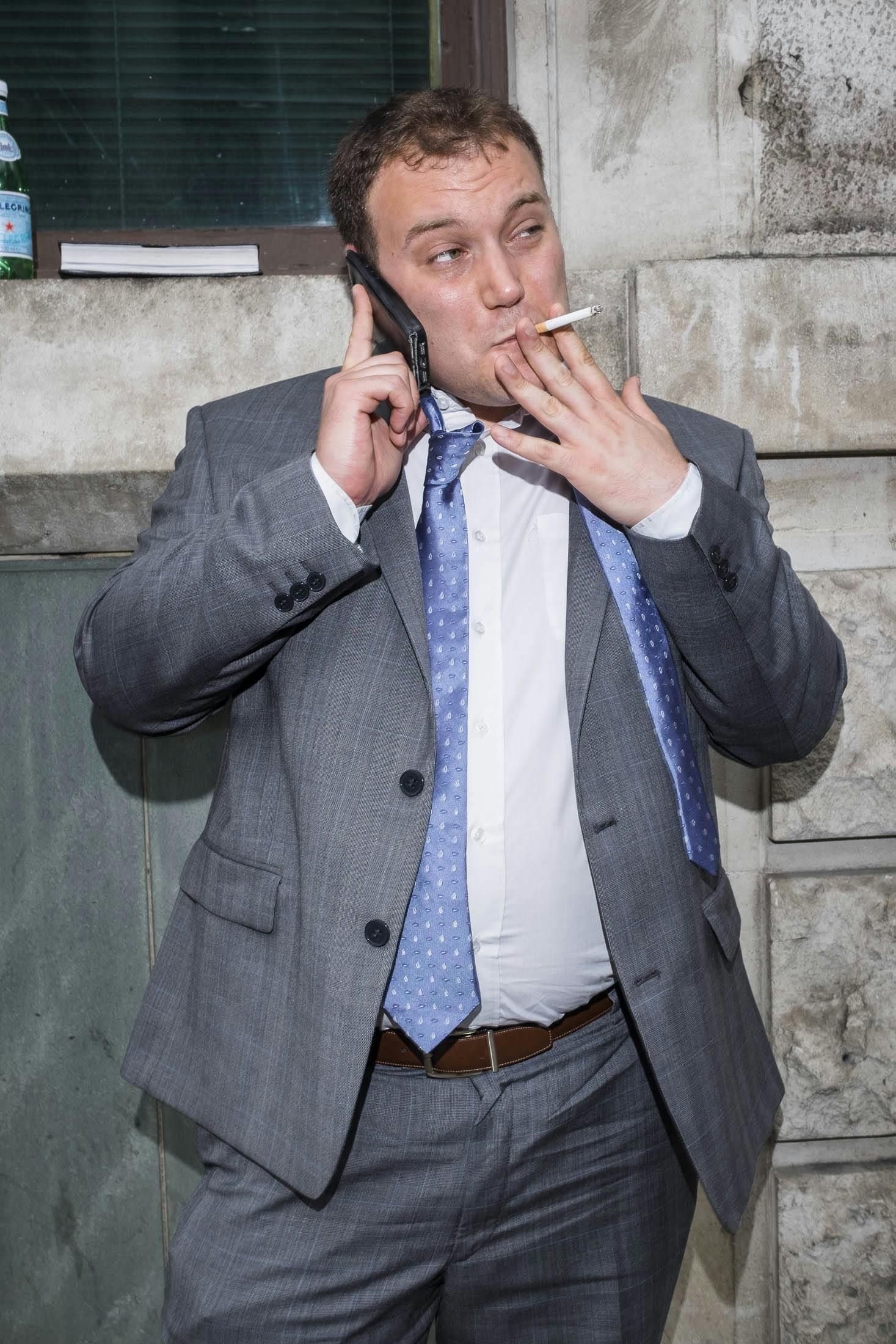 Business man smoking on the phone in grey suit.