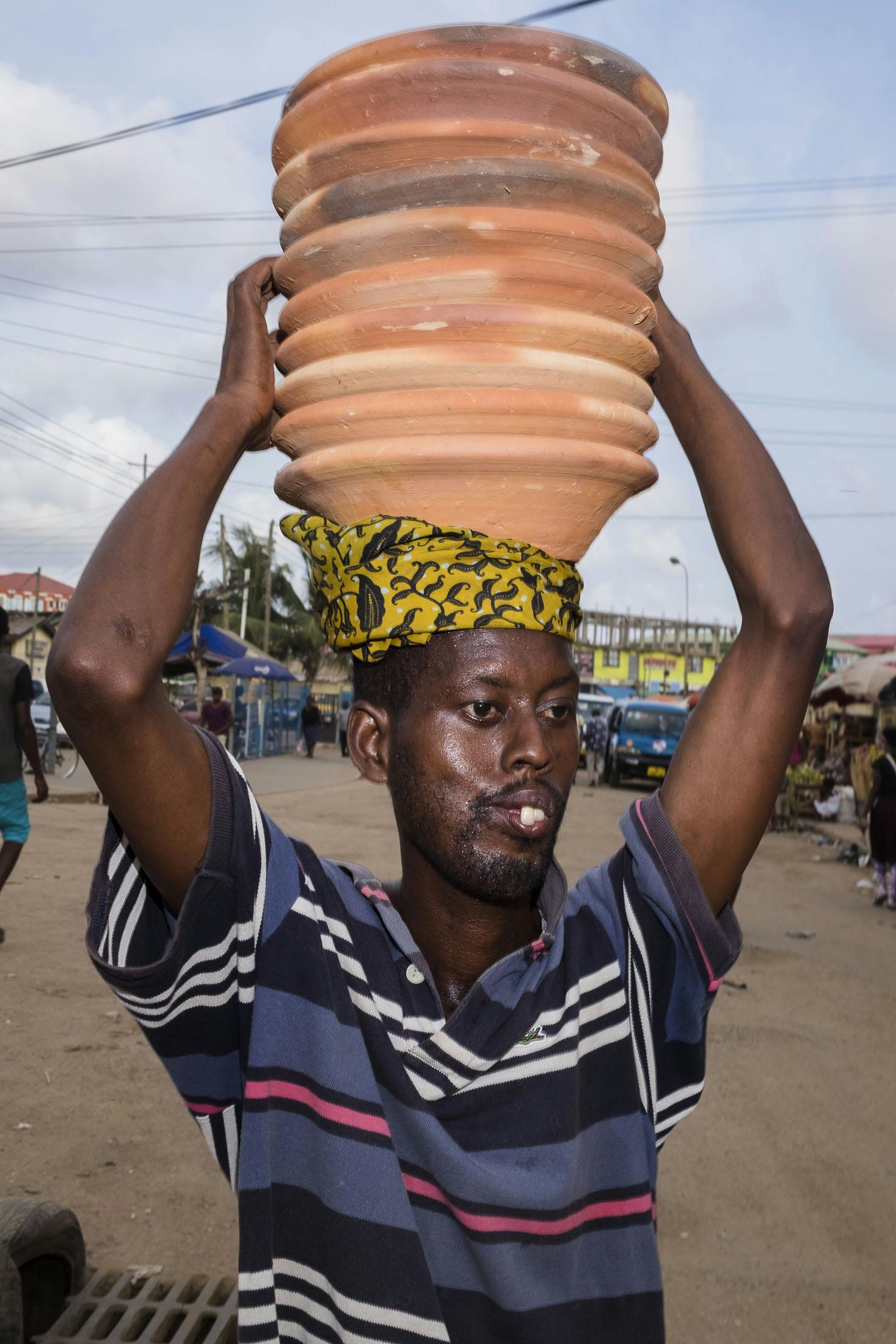 Man carrying pots on his head in Ghana