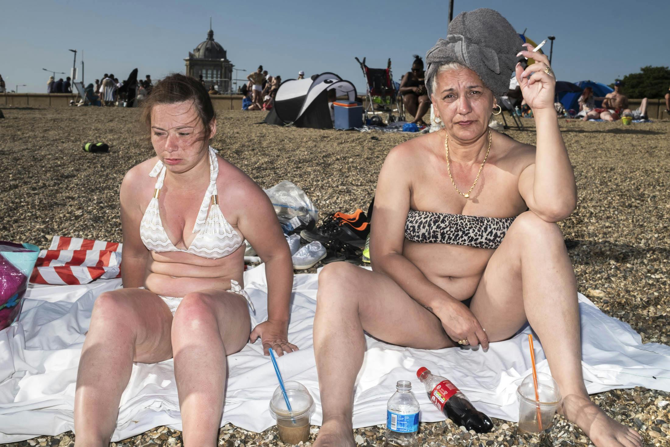 Mother and daughter in bikinis smoking on Southend beach
