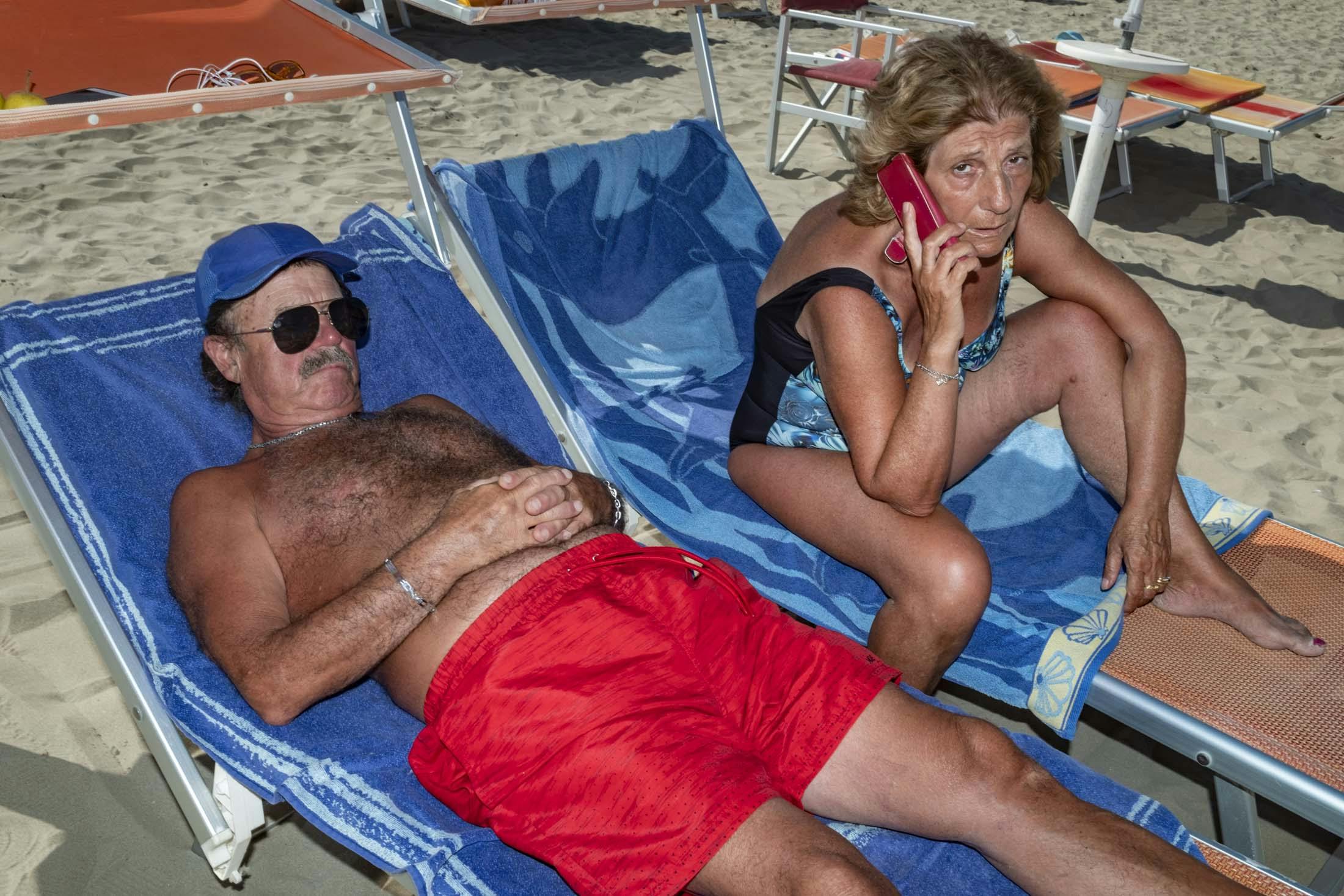 couple on sun loungers on phone 