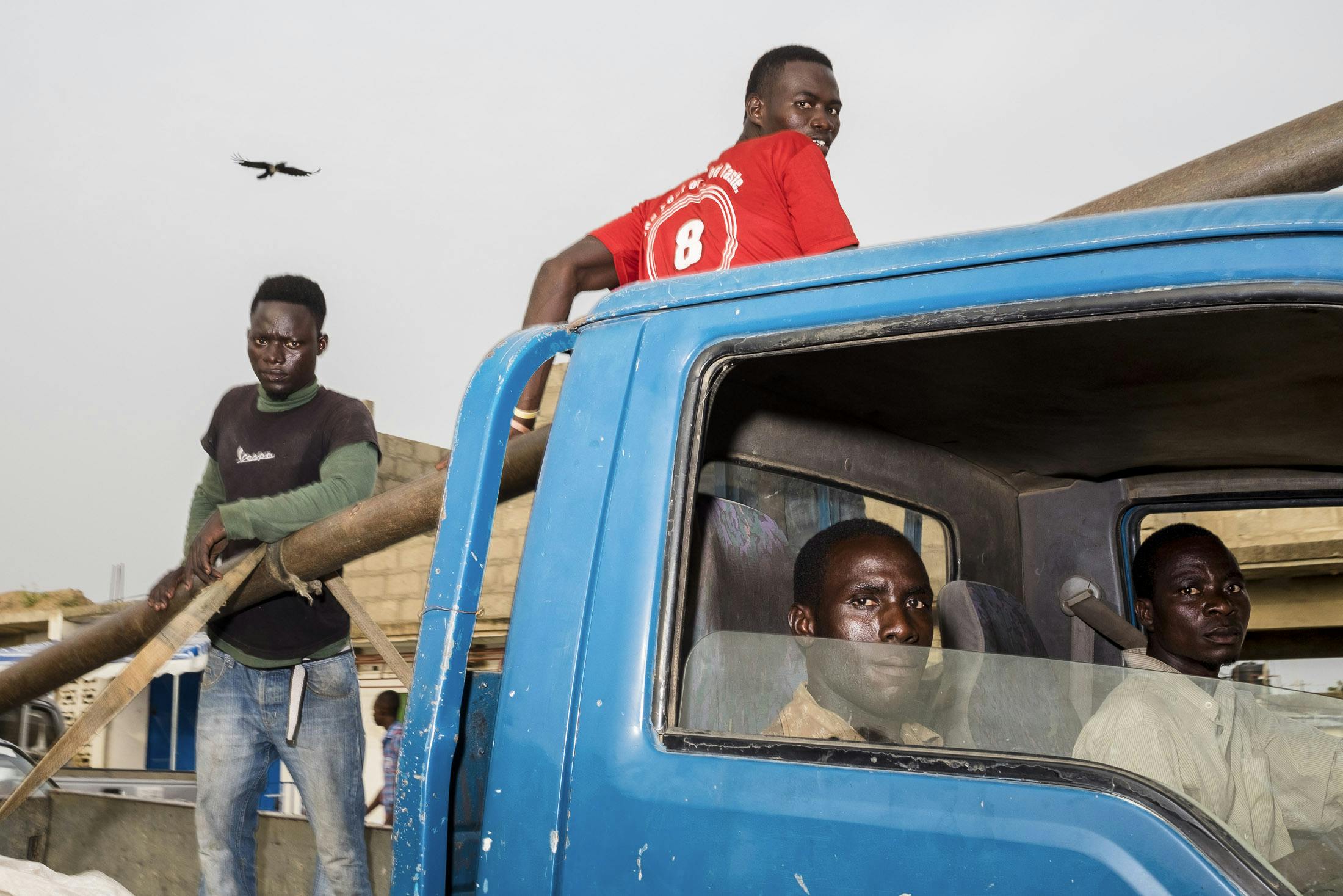 4 men in a blue pick up truck driving in Ghana