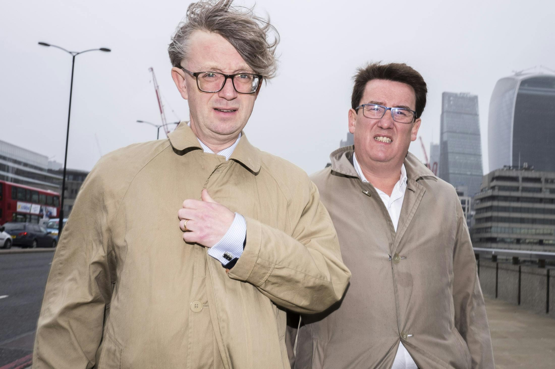 Two business men in beige jackets on London bridge.