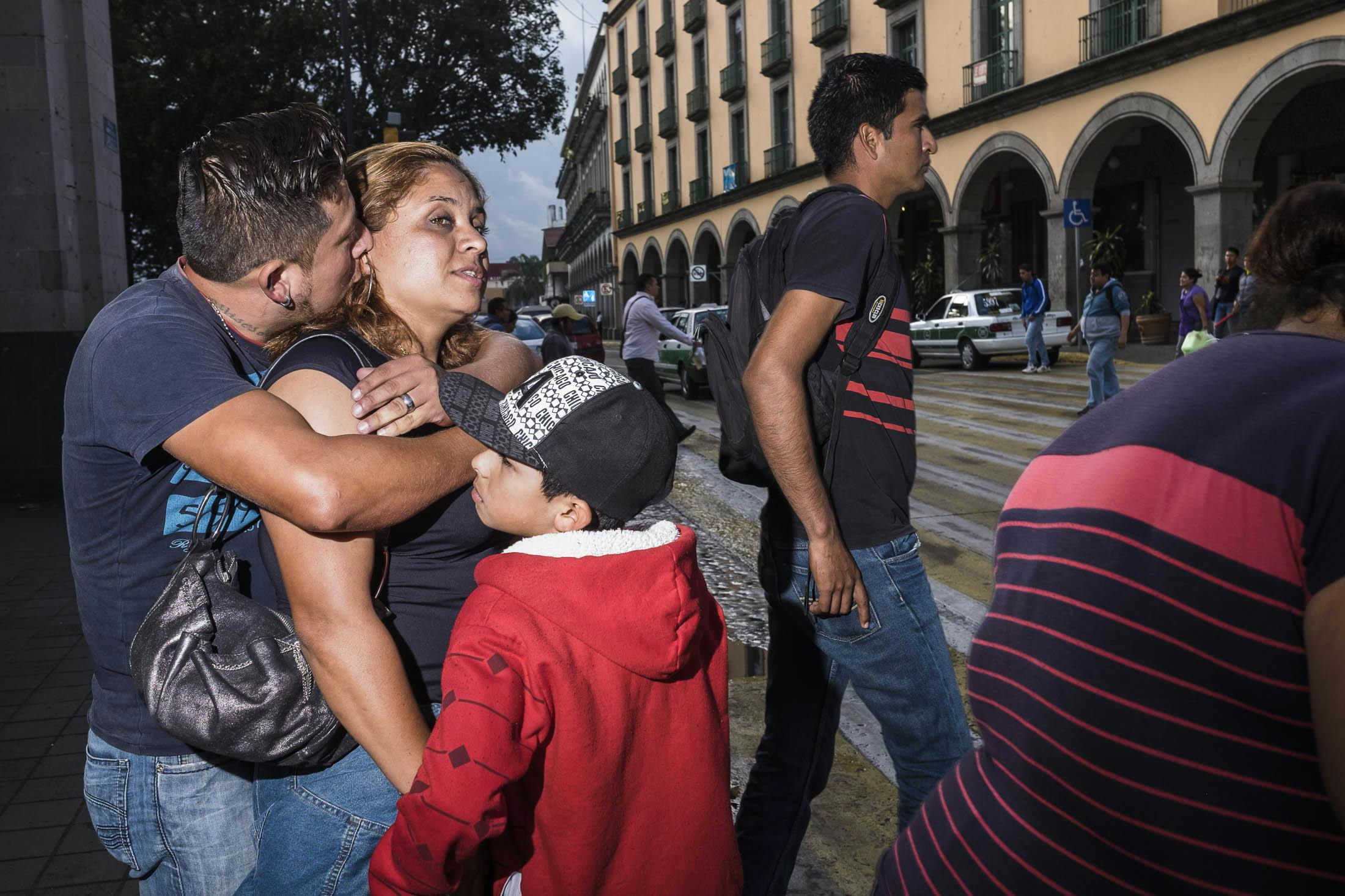 Man holding woman with boy crossing street in Mexico